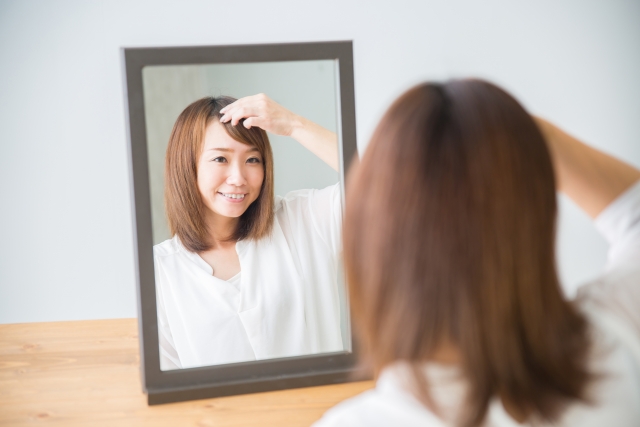 鏡で前髪を見る女性
