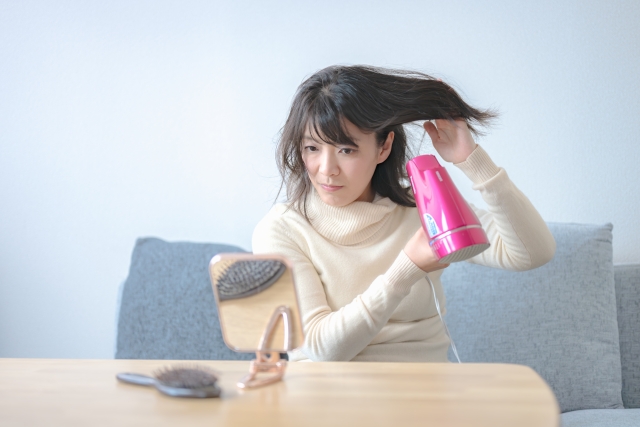ドライヤーで髪を乾かす女性