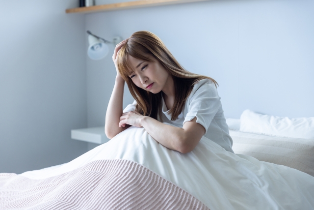 ベッドで頭を抱える女性
