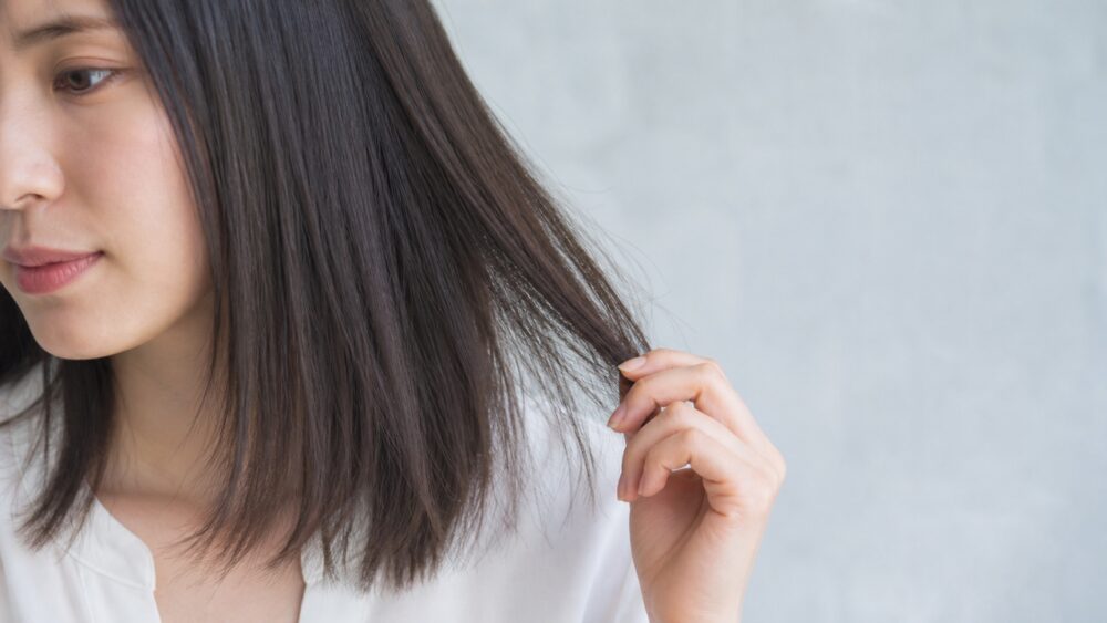 縮毛矯正後の髪の毛先に乾燥や広がりが出ている女性