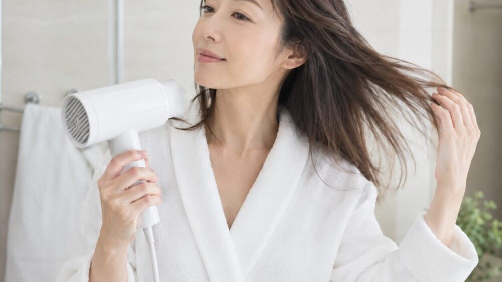 ドライヤーで髪を乾かしている女性