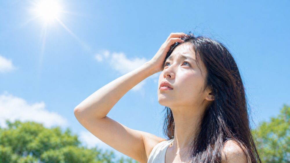 夏の屋外で太陽を見上げる日本人女性