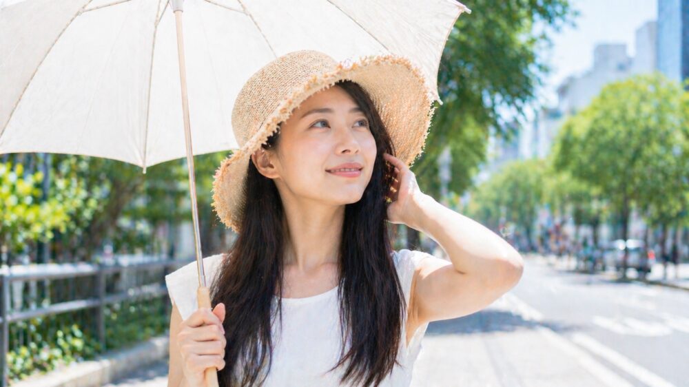 日傘と麦わら帽子で髪を守る日本人女性