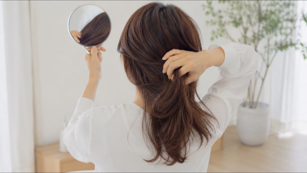 襟足や内側のくせを鏡で確認する女性の後ろ姿