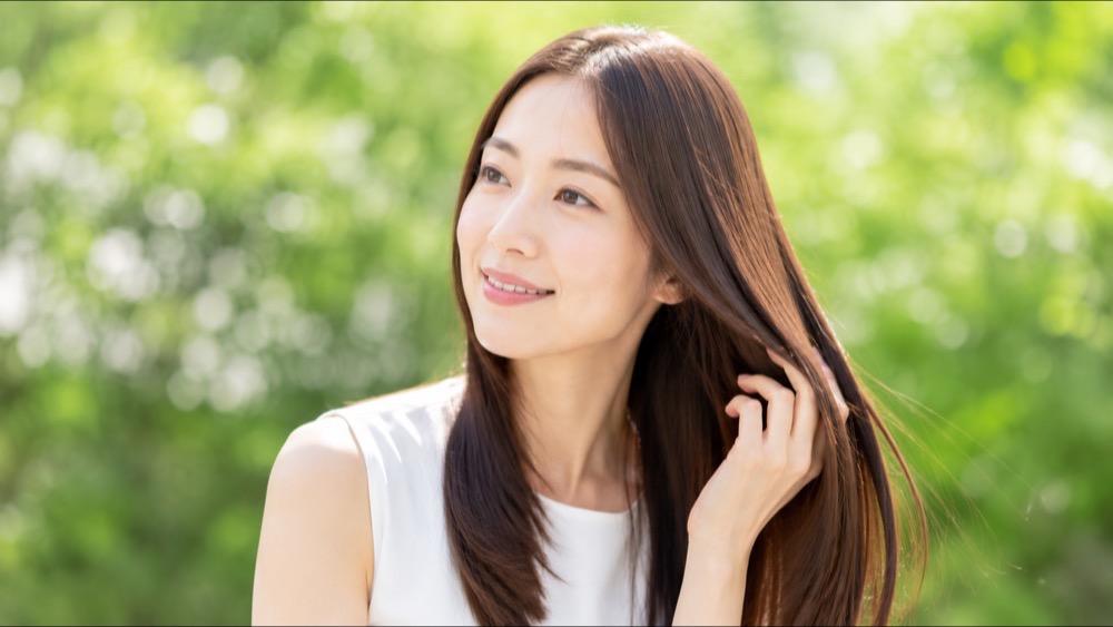 ツヤのある美しいストレートヘアで満足そうに微笑む女性
