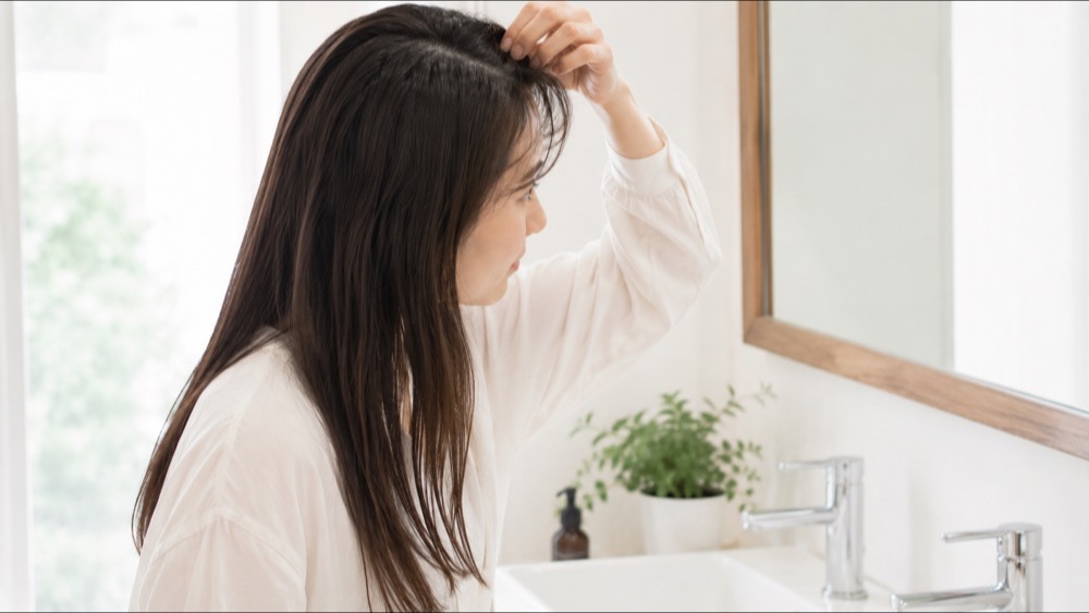 雨の窓辺でうねる髪を気にする女性