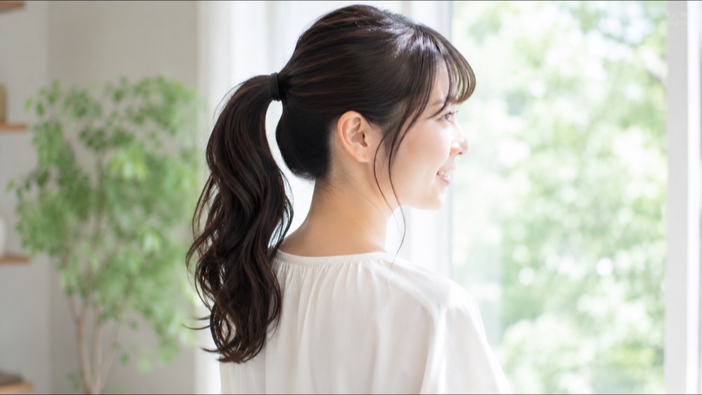 鏡で根元の伸びたクセを確認する女性