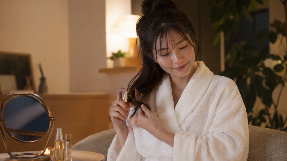 お風呂上がりにリラックスしてヘアケアする女性のイメージ