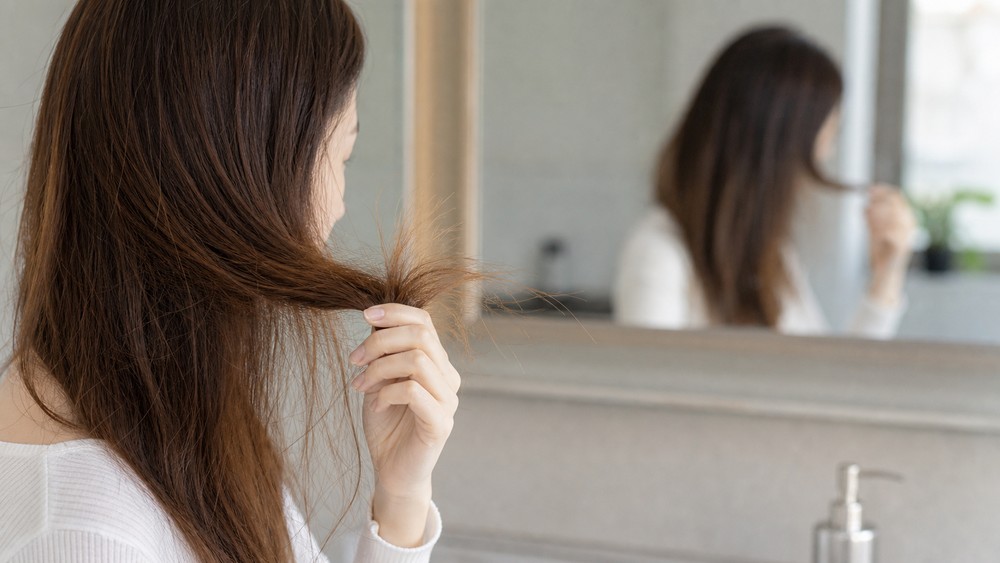 朝に髪のダメージを確認する女性