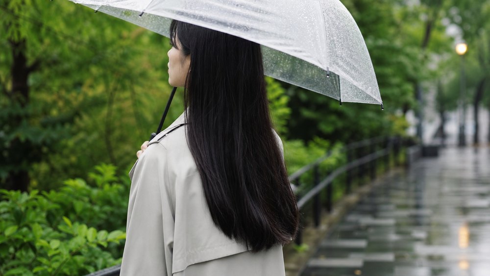 梅雨の雨から縮毛矯正後のストレートヘアを守る女性