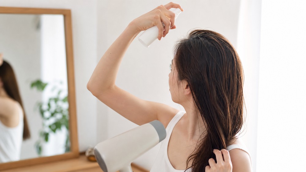 朝に髪の根元を濡らしてリセットする女性