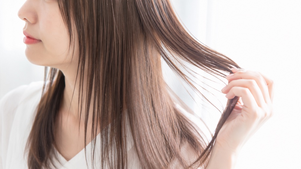 細く柔らかい髪に低温のアイロンを使う女性