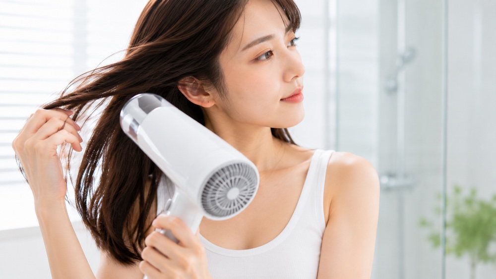 髪を完全に乾かしてからアイロンを使う女性