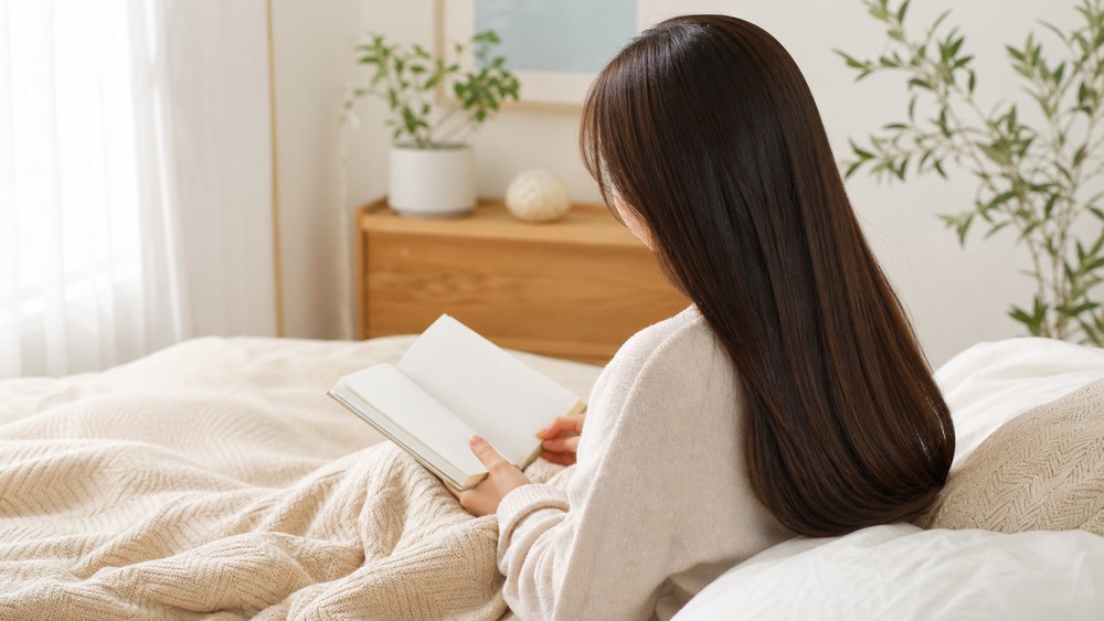 ベッドで読書するなめらかな髪の女性