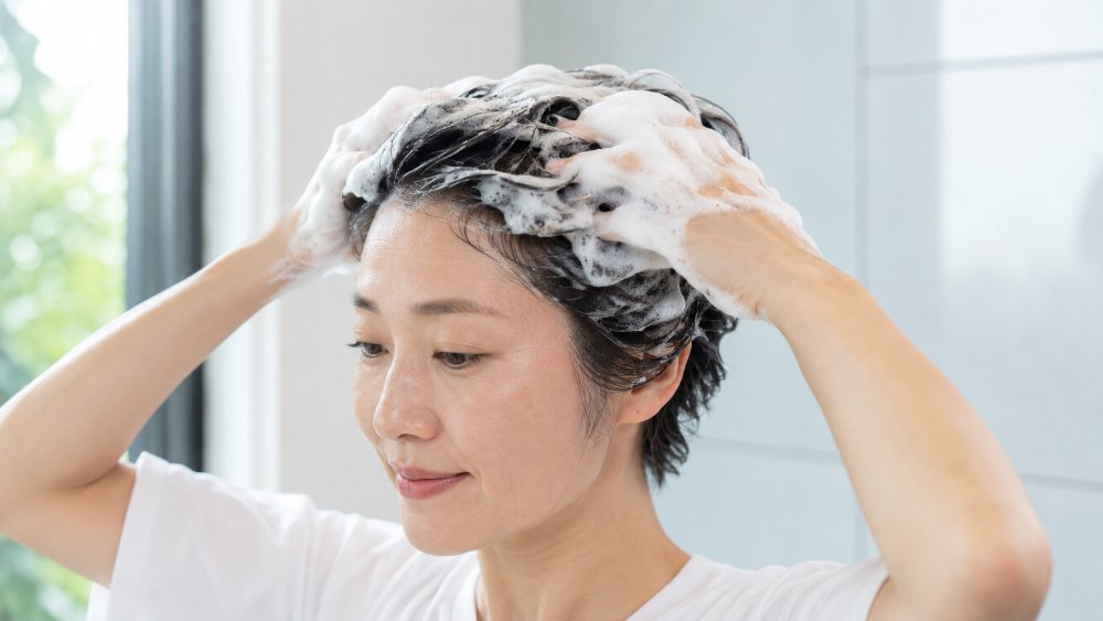 茶色いカラーヘアに乗った白いシャンプーの泡の接写
