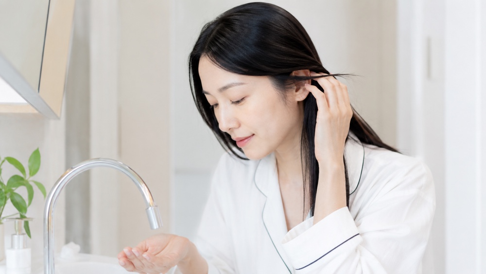 シャワーで髪を予洗いする女性