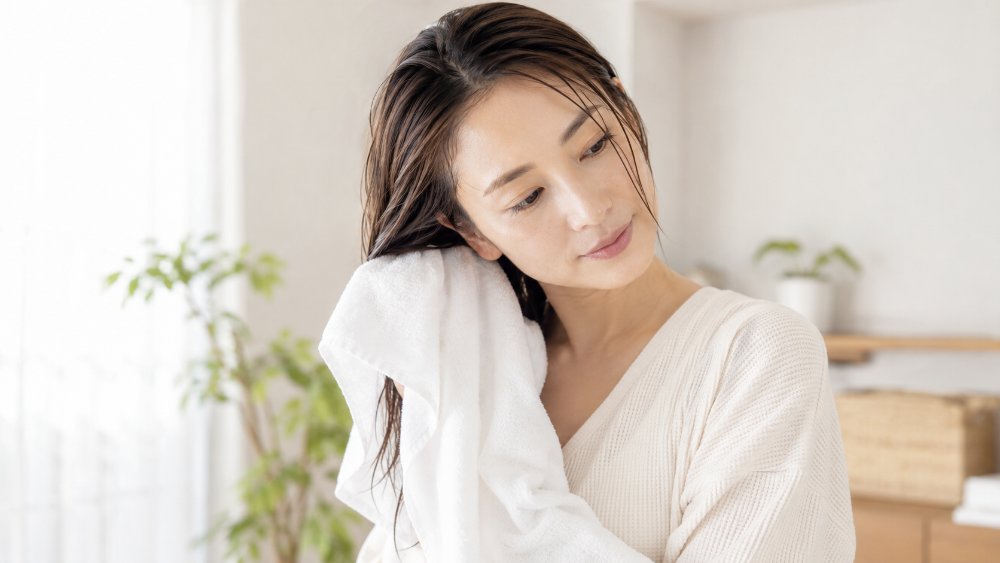 白いタオルの上の濡れた茶髪と水滴、摩擦による色落ちのイメージ