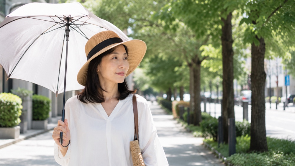 帽子で髪の紫外線対策をする女性