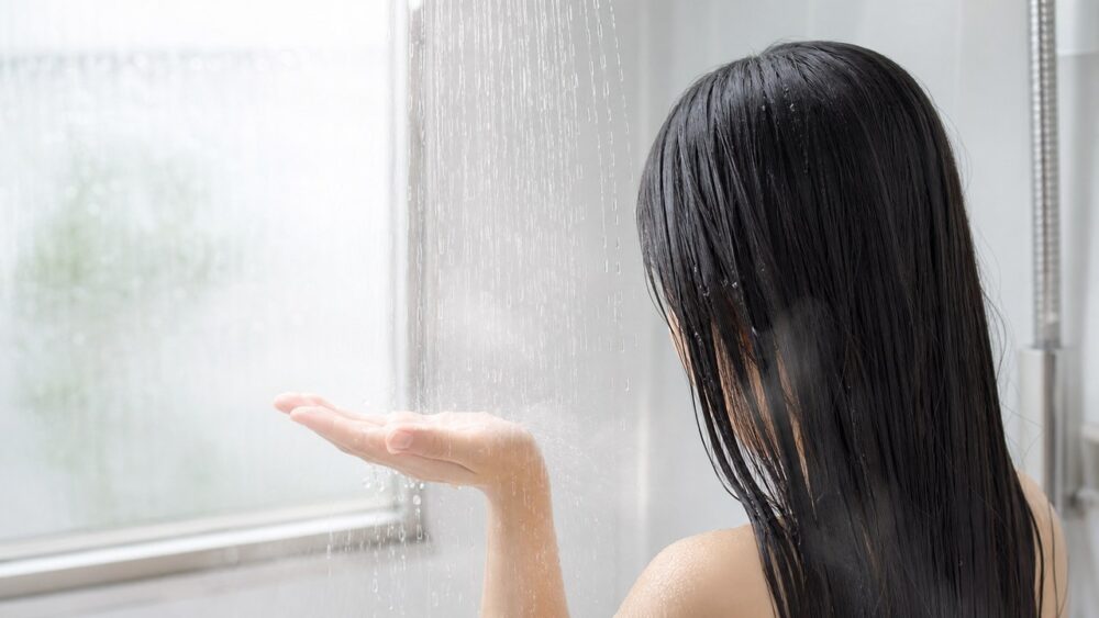 シャワーのぬるま湯で髪をやさしくすすぐ様子
