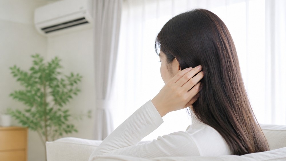 冷房の効いた部屋で髪を触る女性