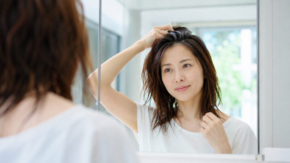 湿気で広がる髪をヘアバームでまとめる30代の日本人女性