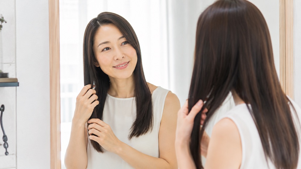 まっすぐなツヤ髪を手でなでて確認する女性