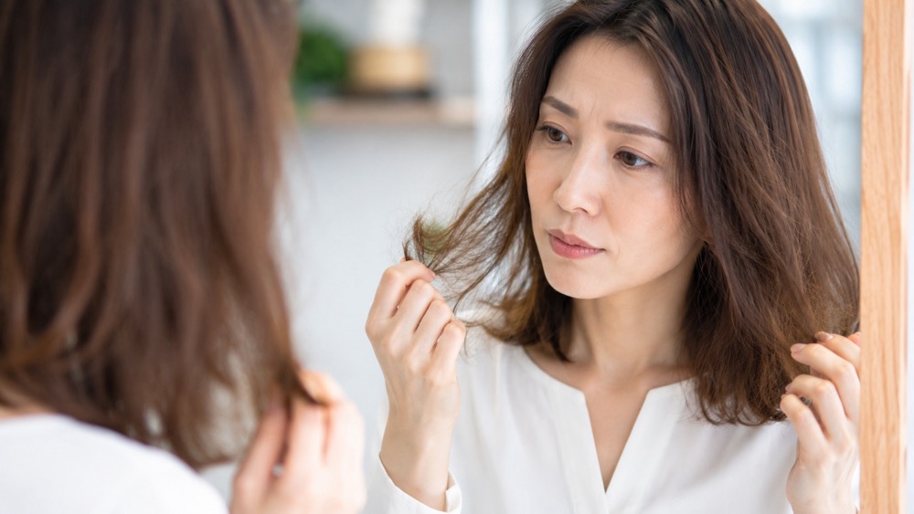 毛先のパサつきを鏡で確認する女性