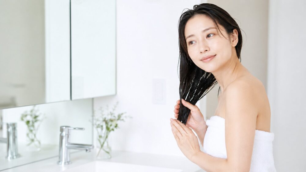 洗い流さないトリートメントを髪になじませる日本人女性