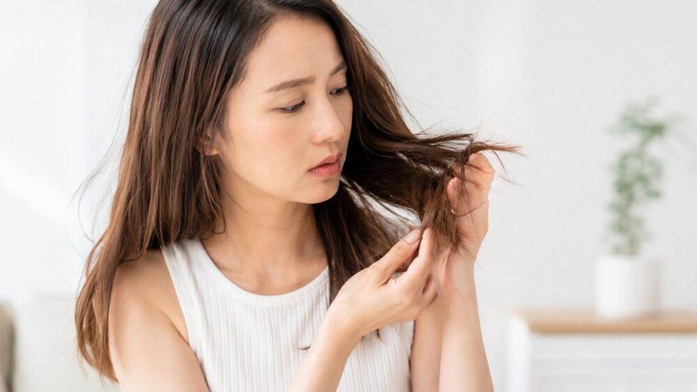 髪のパサつきを気にして手で触れる30代の日本人女性