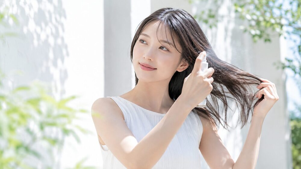 日本人女性が髪にUVスプレーをかけている夏のヘアケア