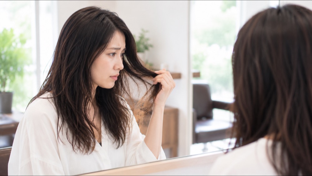 鏡を見て伸びていないクセを気にする女性