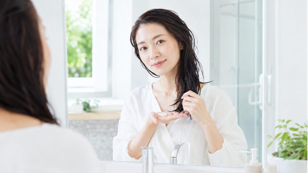 洗い流さないトリートメントを髪につける日本人女性