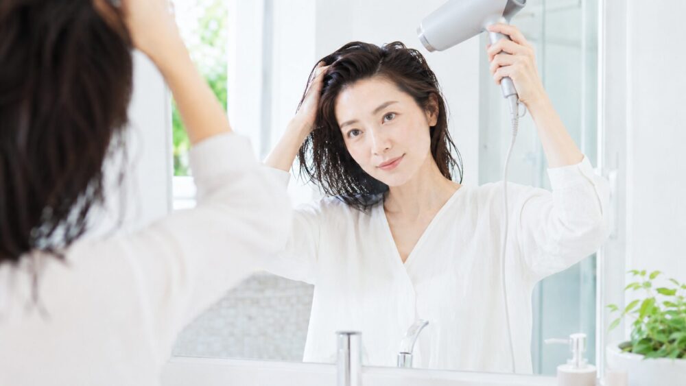 ドライヤーで根元から髪を乾かす日本人女性