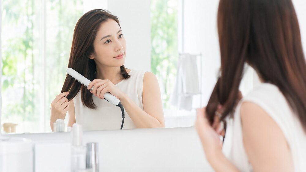 ストレートアイロンで髪を伸ばす日本人女性