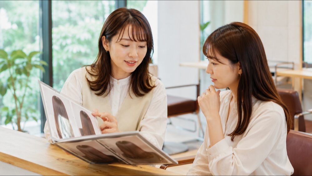 メニュー表を見せながら説明する女性美容師とお客様