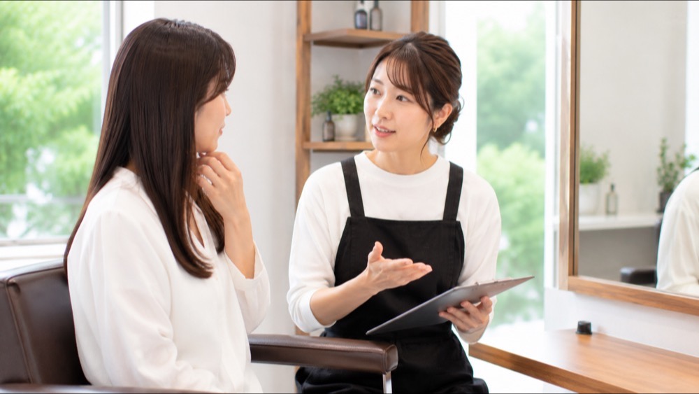 美容室でカウンセリングを受けながら髪を相談する女性