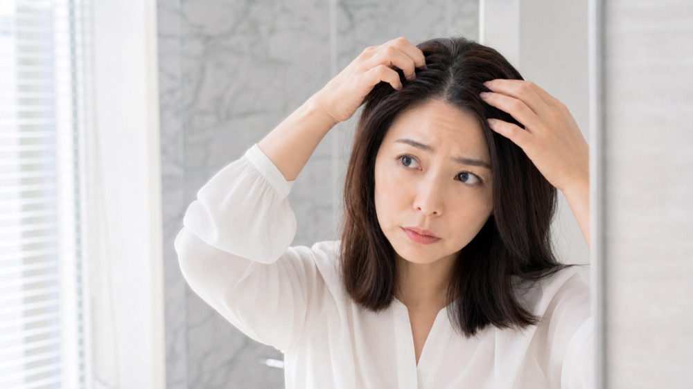 髪の根元のベタつきが気になる女性