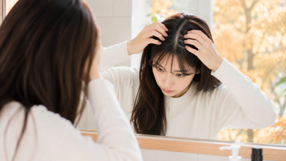 鏡で分け目・頭皮の状態をチェックする日本人女性
