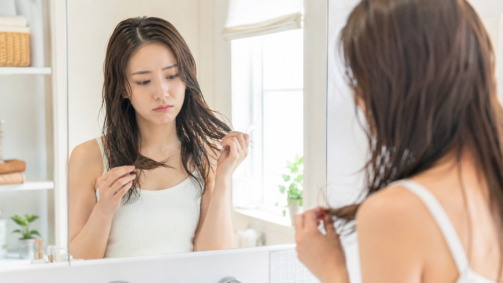 鏡の前で毛先のうねりを確認する日本人女性