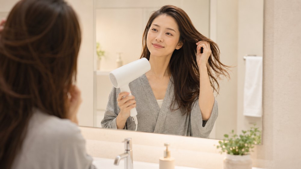 ドライヤーで髪を乾かす女性