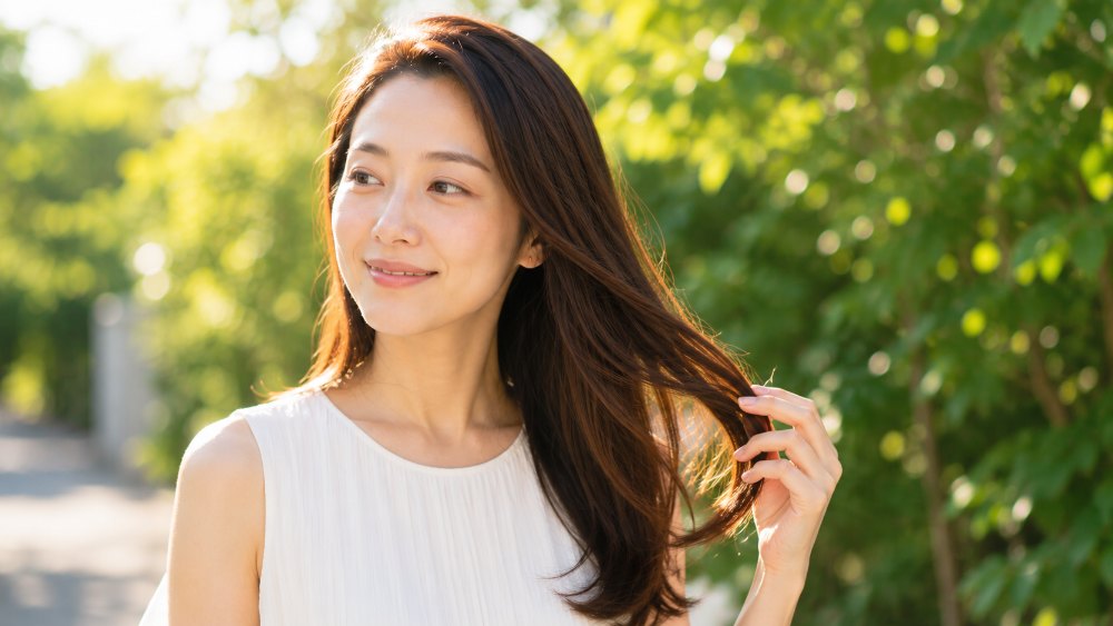 夏の日差しの中でつやのある髪をなびかせる女性