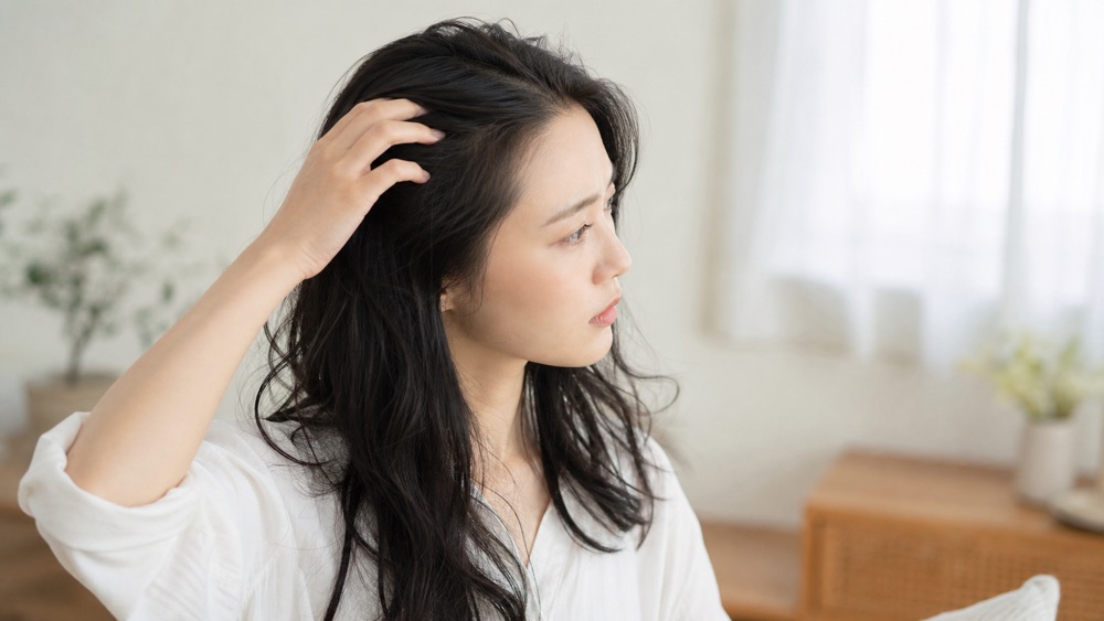 縮毛矯正後に戻った根元のクセを確認する日本人女性