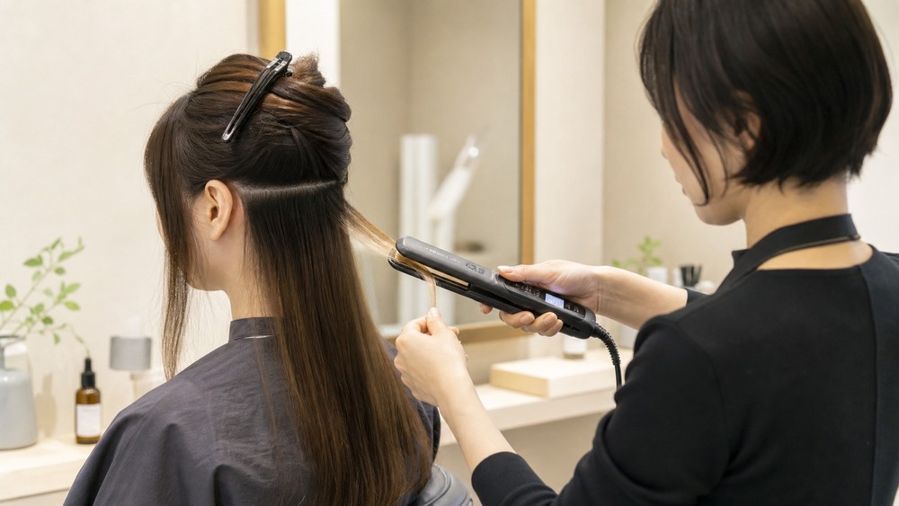 ブリーチ毛へ低い負担を意識してアイロン操作する美容師