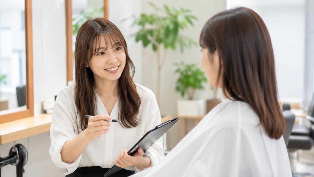 美容室で笑顔でカウンセリングする女性美容師