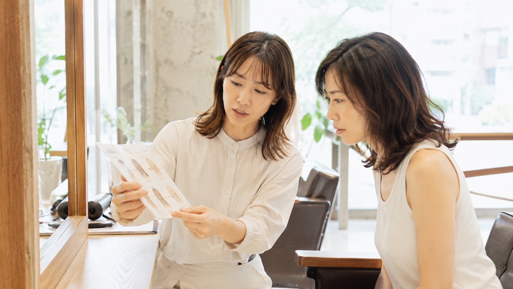 縮毛矯正の仕組みを説明する美容師と相談する女性客