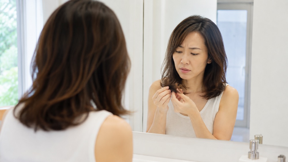毛先の傷みを心配そうに確認する女性