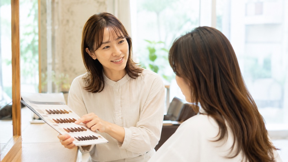 美容室で笑顔でカウンセリングする女性美容師