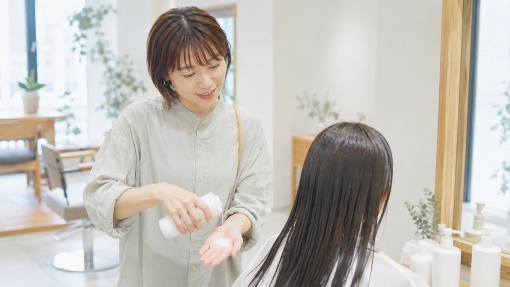 サロンでトリートメントを塗布してもらう女性