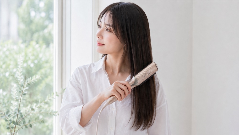 日本人女性がリファ トリートメントアイロンでロングヘアを梳かしているところ