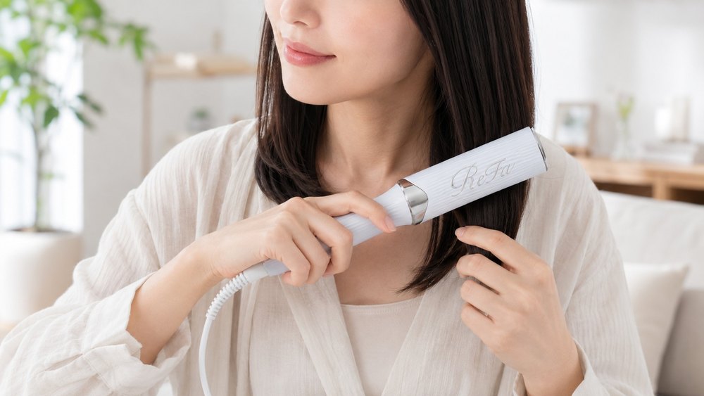 ブラシ型ヘアアイロンで毛先をとかす女性